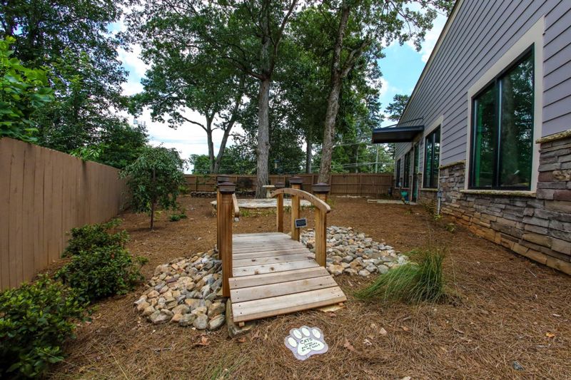 a small wooden bridge in the middle of a fenced in yard
