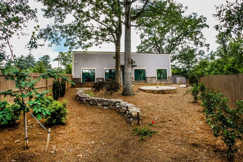 a fenced in yard featuring trees, a fountain and a stone wall