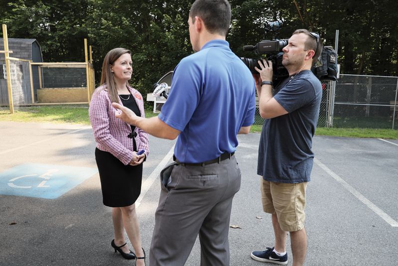 a man films a woman speaking to a reporter