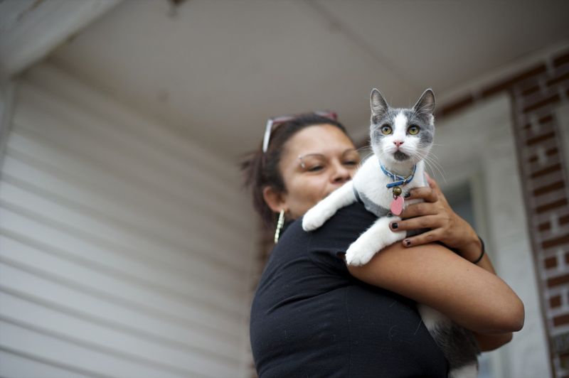 a woman holding a cat that is looking over her shoulder