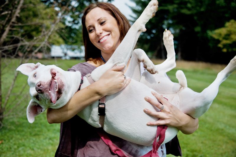 a smiling woman cradles a happy large dog