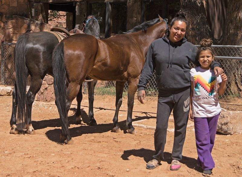 a woman and a child pose in front of two horses