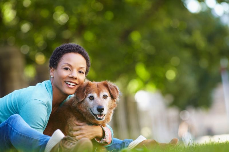 a woman leans forward to hug her dog