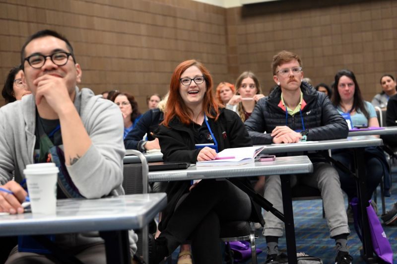 a group of attendees smiling as they watch a presentation