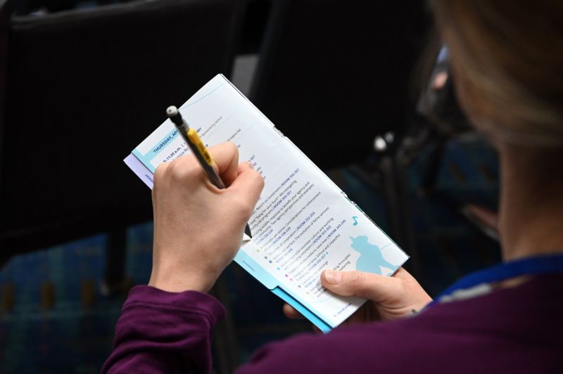 a person marks a line in the expo pocket guide with a pencil