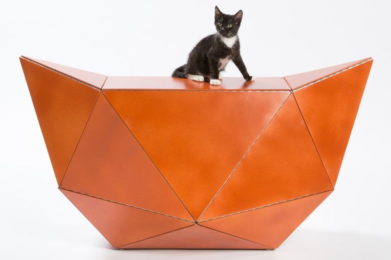 a cat sitting atop an orange geometric structure