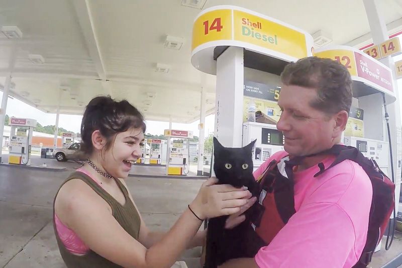 a man hands over a cat to its smiling owner