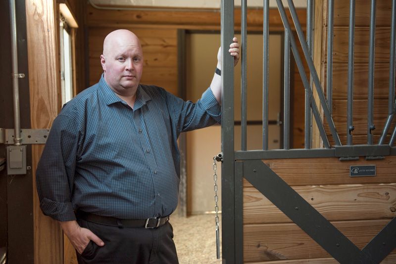 a man stands in front of a horse pen