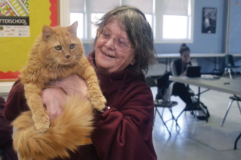a woman smiles and holds up her cat