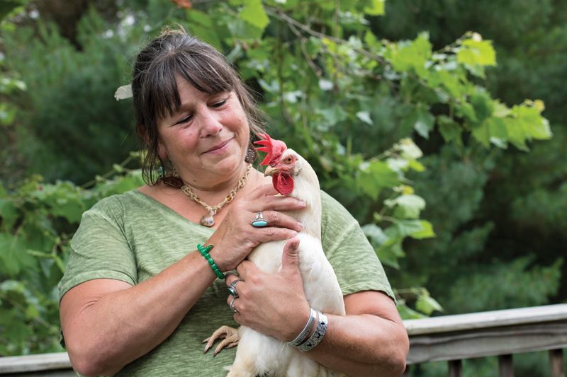 a woman holds up a rooster