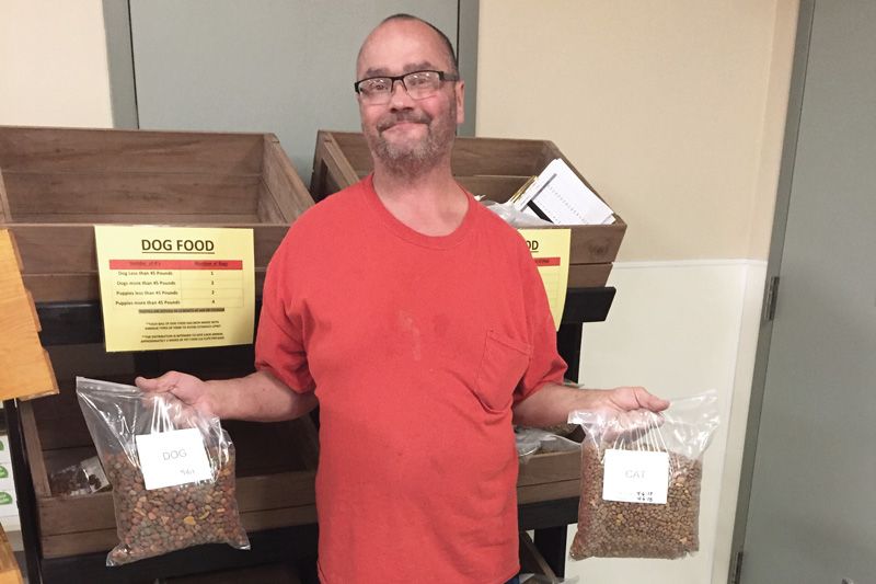 a man holds up bags of cat and dog food