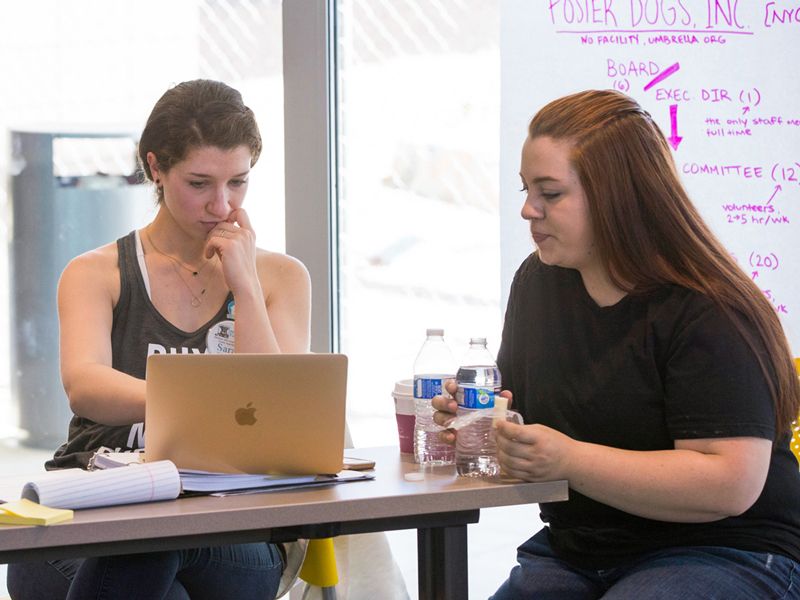 Two women in discussion as they look at a laptop screen