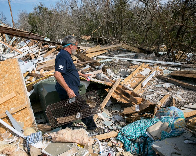 a man walks through the rubble of a destroyed home