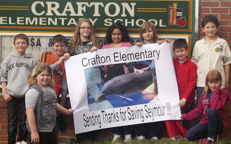 a group of students hold up a poster of a dolphin