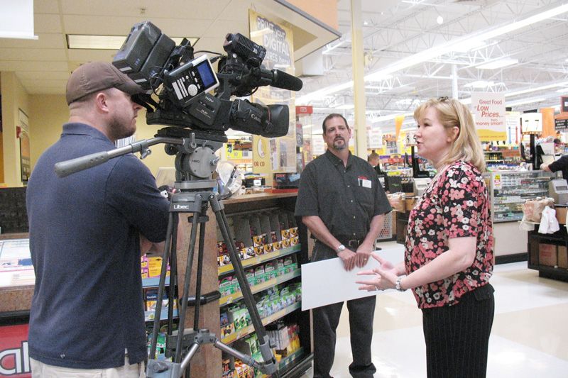 a woman being interviewed in front of a camera in the grocery store