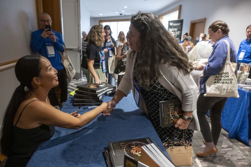 two women shake hands across a table