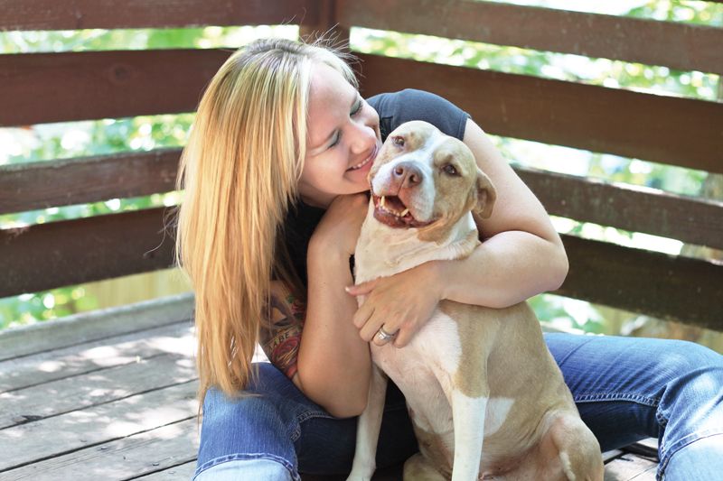 a smiling woman embraces her dog