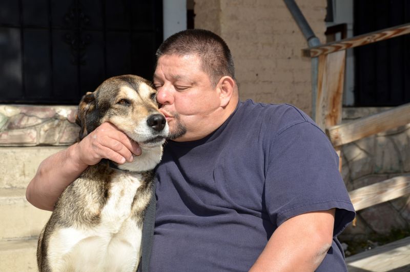 a man kissing his dog's head