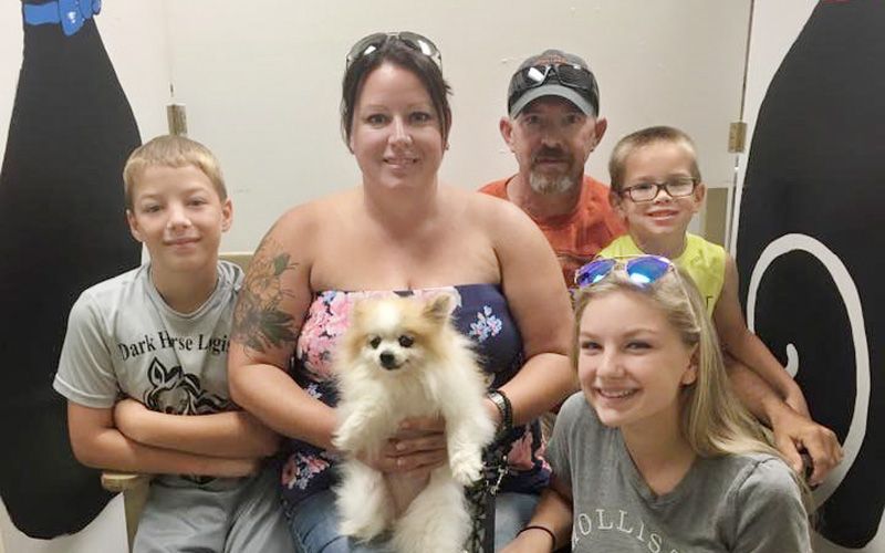 A family poses with their newly-adopted small dog