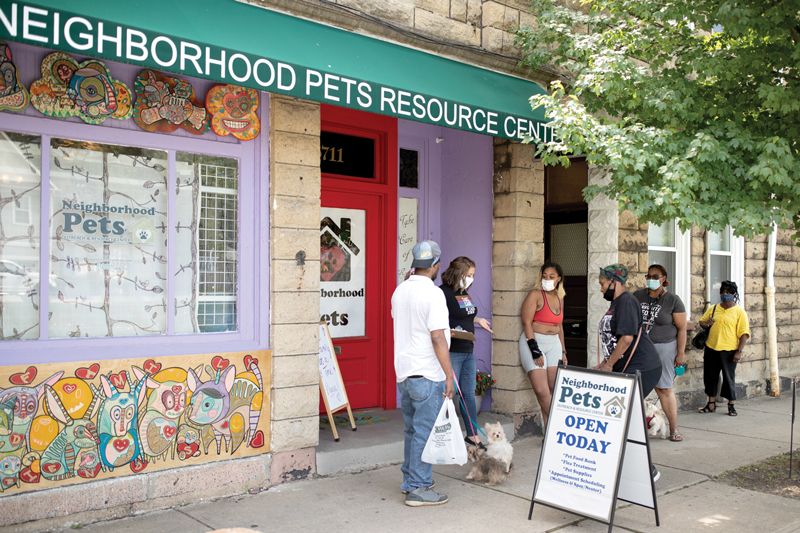 a group of people gathered outside the neighborhood pets building