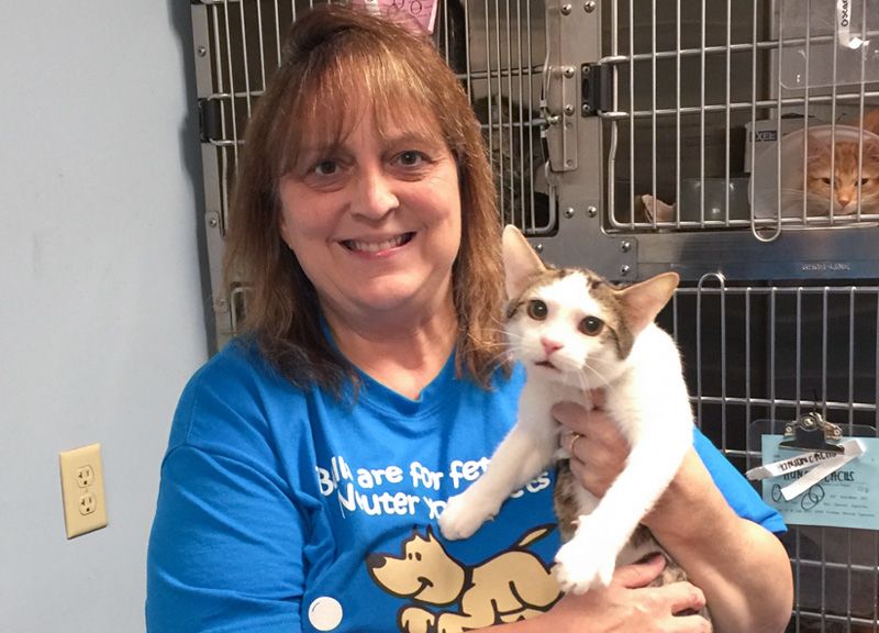 a woman holds up a cat in a shelter