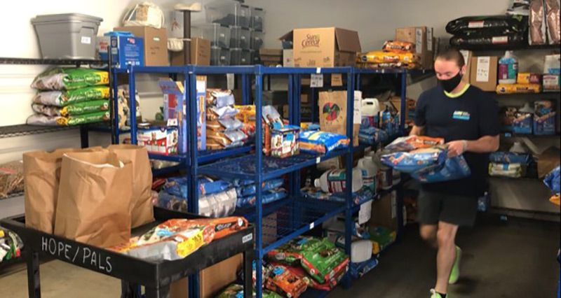 Image of Hunter, a volunteer with Meals on Wheels Central Texas loading up pet food to go out to clients. 