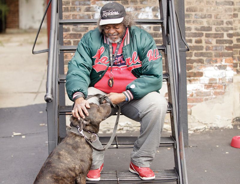 A man sitting on a fire escape pets his dog