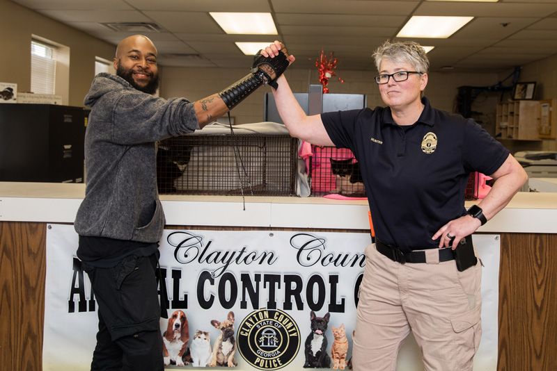 a man and animal control officer clasp hands above an animal control sign