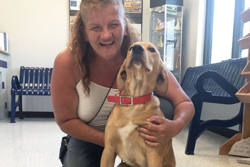 a woman smiles and poses with her dog