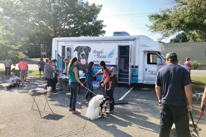 a group of people and pets gathered around a mobile vet clinic