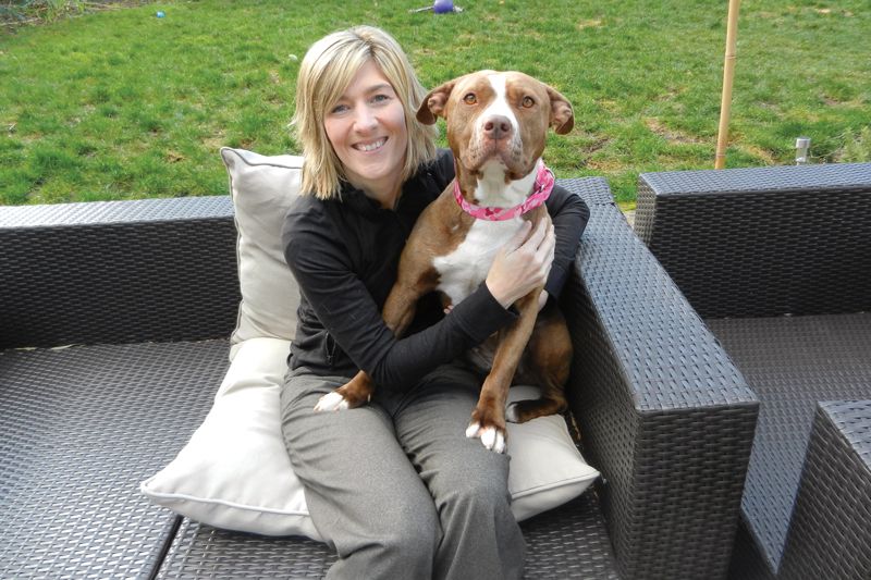 a woman sits with a larger dog on her lap
