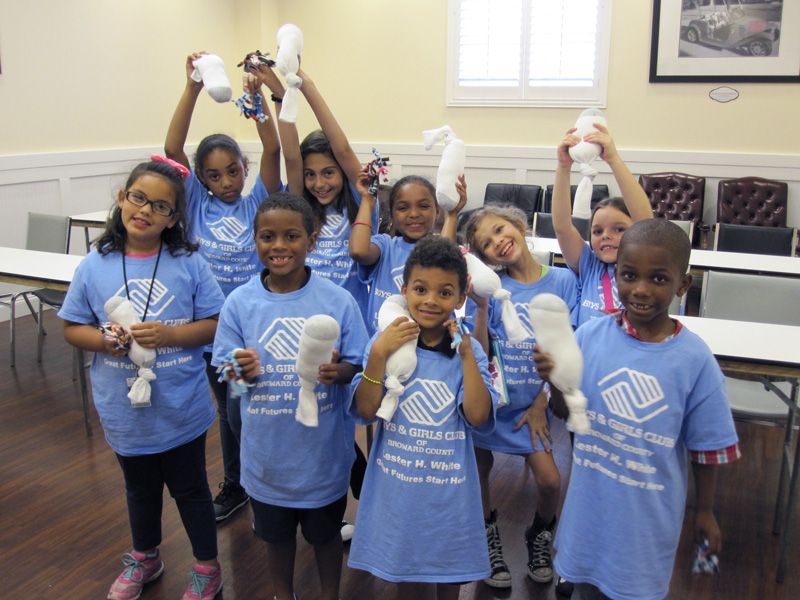 a group of smiling children hold up sock toys