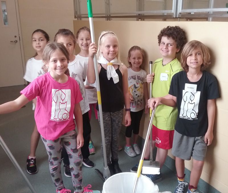 A group of children pose with cleaning supplies