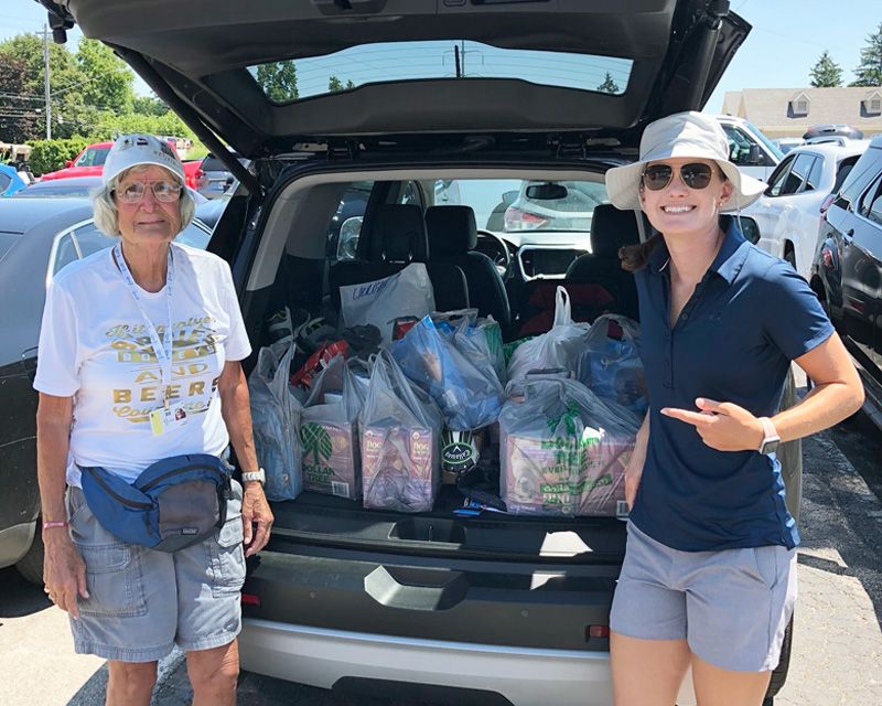 Two women pose with a trunk full of pet supplies