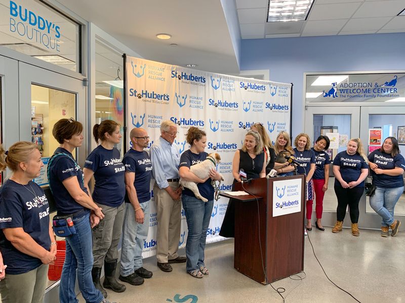 staff from st huberts and humane rescue alliance stand around a podium