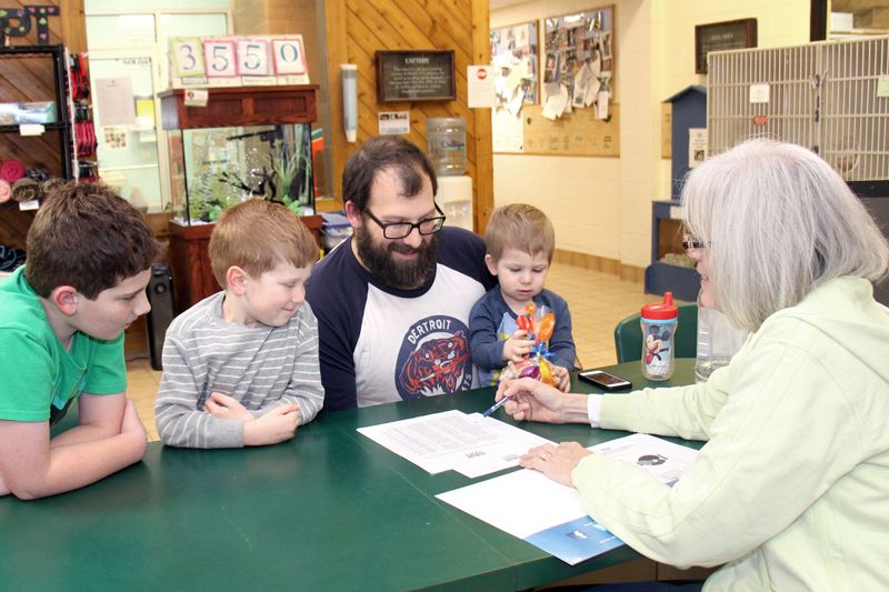a man signs adoption papers while his three sons look on