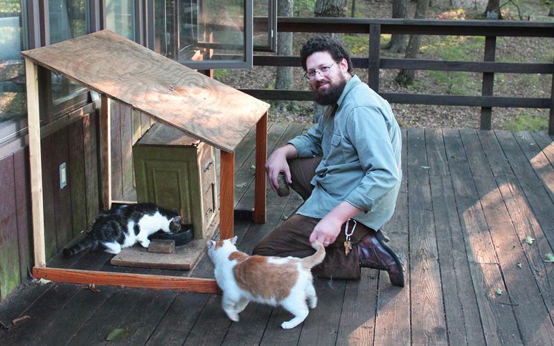 a man sets out food on his deck for community cats