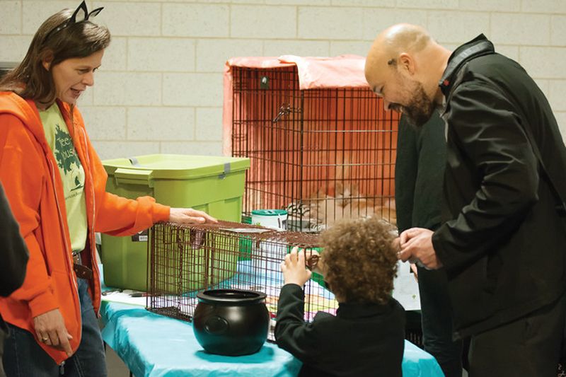 a woman shows a child and adult how to use a cat trap