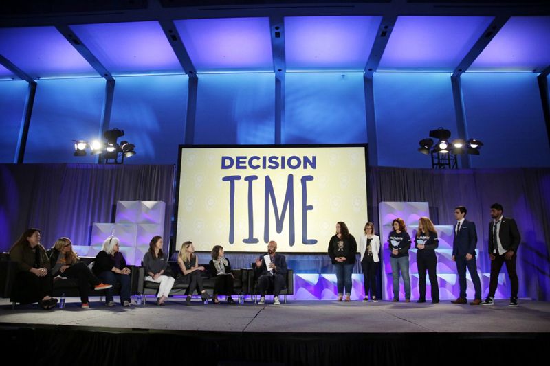 a group of contestants stand on stage while the judges deliberate