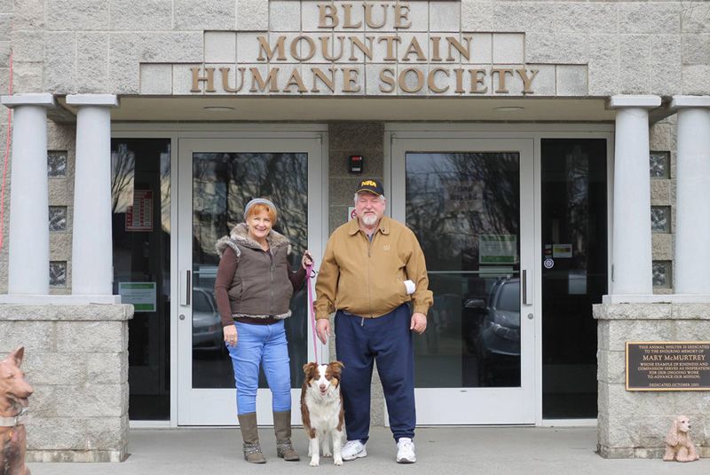 a couple in front of their local humane society with their newly adopted dog