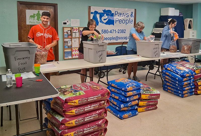 people separating large bags of pet food into smaller bags