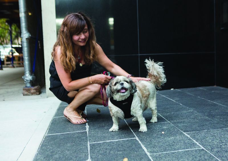 a woman kneels to pat a dog on the back