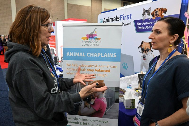 two women talking in front of an animal chaplain sign