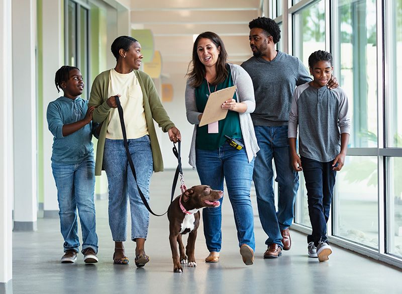 a family walking with their dog down a shelter hallway