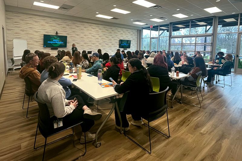 a group of people sitting at tables listening to a presentation