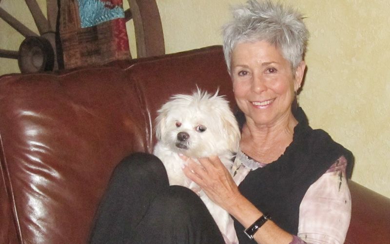 a woman sitting on a couch with her dog