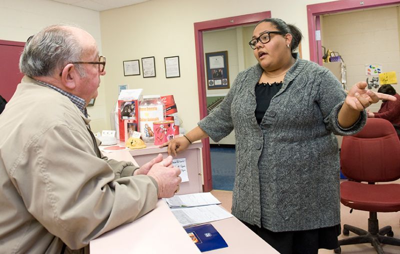 a woman standing behind a counter talking to an older man