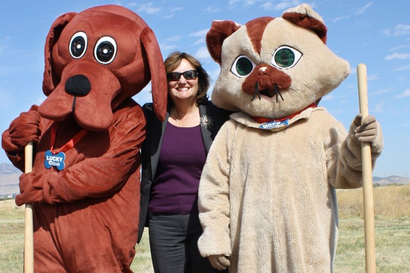a woman standing between dog and cat mascots