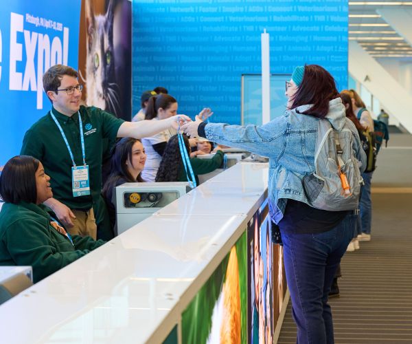Staff handing badge to an attendee at registration desk