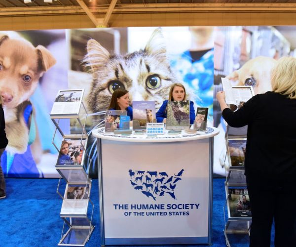 two people sitting at a humane society booth at expo